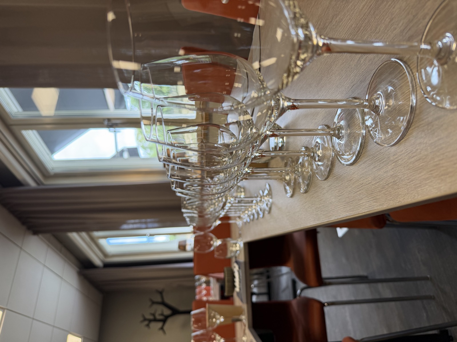 Wine glasses lined up along the table, daylight from the windows behind