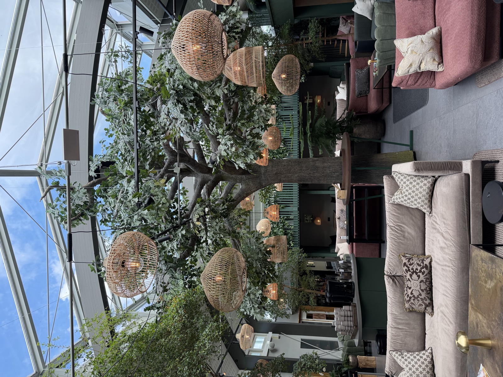 The glass-roofed garden at Sånga-Säby, with a large oak and rattan lamps